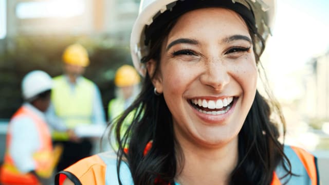 Smiling woman with hard hat and safety jacket